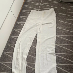 Vita kostymbyxor från Nelly - Snygga vita kostymbyxor från Nelly i rak modell. Storleken är 38 men kan användas som 36 också. De ör i en god skick och använt knappt