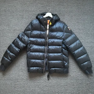 Svart dunjacka Parajumpers Sheen L - Nästan ny Parajumper – dragkedja trasig  Beskrivning: Säljer min exklusiva Parajumper-jacka som endast är använd en gång. Tyvärr är dragkedjan trasig, men jackan är annars i absolut toppskick – ser helt ny ut. Den är varm, snygg och av hög kvalitet, perfekt för höst och vinter. Ett riktigt fynd om du kan fixa dragkedjan själv eller vill ha en unik jacka till ett lägre pris än nypris. Passa på, den här modellen är eftertraktad och säljs sällan!  Storlek: L Färg: Svart 