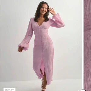 Rosa långklänning med v-ringning nelly - Superfin långklänning i rosa med v-ringning och långa puffärmar. Klänningen har knappar framtill och en slits som ger en snygg touch. Tillverkad i ett lätt, strukturerat material som känns luftigt och bekvämt. Perfekt för vår och sommar! Köpt på nelly för nypris på 799kr + frakt. Endast prövad