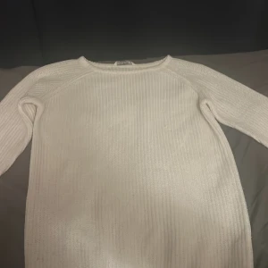 Vit ribbstickad tröja från Cubus - Säljer en vit ribbstickad tröja från Cubus i storlek 158. Tröjan har lång ärm och är tillverkad i 100% akryl. Enkel och stilren modell med rund halsringning, perfekt för lager-på-lager under kyliga dagar.