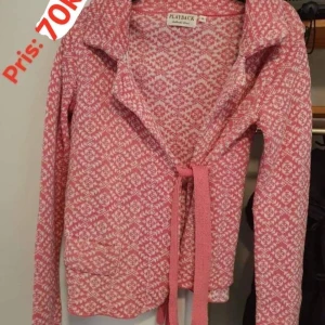 Rosa och vit kofta från Playback strl: S - Säljer en mysig rosa och vit kofta från Playback med snyggt mönster och knytband framtill. Koftan har långärmad design och är stickad i mjukt material, perfekt för att hålla värmen. Passar dig som gillar färgglada och unika plagg.