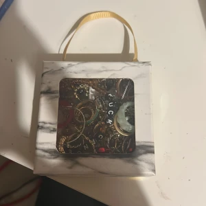 Mixad box med örhängen och ringar - En box fylld med olika örhängen och ringar i flera färger som guld, silver, röd, grön och turkos. Innehåller både chunky och tunnare modeller, några med pärlor och bokstavspärlor. Perfekt för dig som vill ha unika accessoarer och mixa stilar.