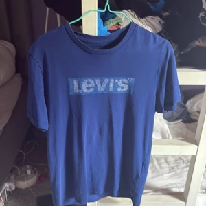 Blå Levi's t-shirt med logga - Snygg blå t-shirt från Levi's med klassisk logga tryckt på bröstet. T-shirten har rund halsringning och korta ärmar. Tillverkad i mjuk bomull som är skön att ha på sig hela dagen.