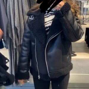 Svart teddyjacka med dragkedja XS - Säljer en svart teddyjacka i storlek XS med mysigt foder och detaljer i fuskpäls. Jackan har sned dragkedja, två fickor och en snygg spänndetalj vid kragen. Perfekt för kalla dagar och ger en cool vibe till din outfit.