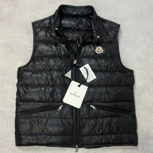 Moncler gui down vest - – Condition: 10/10 - brand new with tags  - Size: 3/L  – Retail price: 9260 SEK  Please note that Moncler runs small, we recommend going up one size from your usual size.