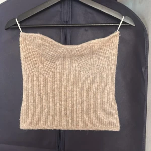 Beige stickad tubtopp från Gina Tricot - Säljer en beige stickad tubtopp från Gina Tricot i storlek S. Toppen är ribbstickad och har en mjuk, mysig känsla med en enkel och stilren design. Perfekt att styla med jeans eller kjol för en trendig look.