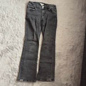 Grå bootcut jeans från Gina Tricot - Snygga grå jeans från Gina Tricot i bootcut-modell. Jeansen har klassisk femficksdesign och dubbla silverknappar i midjan. 