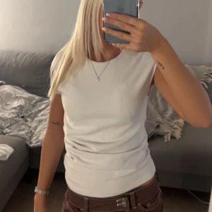 Vit ärmlös topp från Zara - Säljer en stilren vit ärmlös topp från Zara. Toppen har rund halsringning och är i mjuk bomullskvalitet. Enkel och clean design som är lätt att matcha med olika outfits. Perfekt för dig som gillar minimalistisk stil.