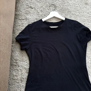 Mörkblå t-shirt från Intimissimi i bomull - Klassisk mörkblå t-shirt från Intimissimi i 100% Supima bomull. Modellen är enkel med rund halsringning och korta ärmar, perfekt för en clean och stilren look. Skön passform som sitter snyggt utan att vara för tight. Storlek M! Sitter skönt på mig som är mellan S-M