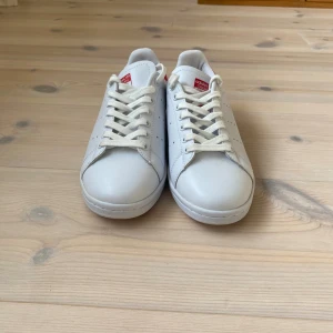 Adidas Stan Smith vita sneakers röd detalj - Klassiska Adidas Stan Smith sneakers helt splitter nya vid frågor eller funderingar är det bara att höra av sig det kommer ut ett par likadana skor med blåa detaljer!