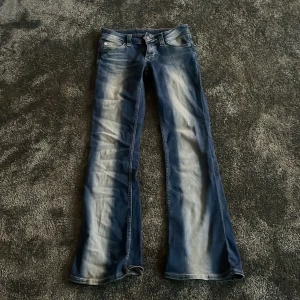 Blå bootcut jeans från Cheap Monday - Säljer ett par blå bootcut jeans från Cheap Monday med snyggt slitna detaljer och klassisk femficksmodell. Jeansen har en markerad bootcut-passform och coolt Cheap Monday-märke bak i midjan. Perfekta för dig som gillar retro vibe och vill sticka ut. Nyss köpta.