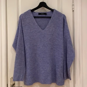 Ljuslila stickad V-ringad tröja Vero Moda - Supermysig ljuslila stickad tröja från Vero Moda med V-ringning och lång ärm. Tröjan har en loose passform och ribbad struktur, perfekt för lager-på-lager under kyliga dagar.