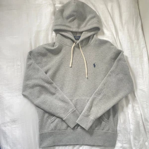 Grå hoodie från Polo Ralph Lauren - Grå hoodie från Polo Ralph Lauren med klassisk huva och vit snörning. Tröjan är i storlek S och har inga defekter! Skriv för funderingar 😊
