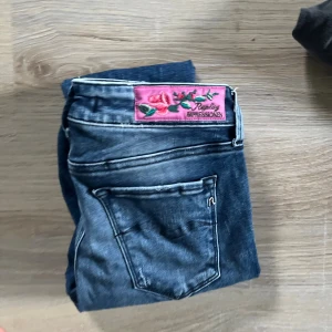 Replay jeans med broderad patch - Snygga blå jeans från Replay med en unik rosa patch och broderade blommor på bakfickan. Jeansen har klassisk femficksdesign och är tillverkade i slitstarkt denim. Perfekta för dig som vill sticka ut med coola detaljer.