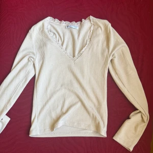 Beige ribbad långärmad topp Karol basic - Säljer en beige ribbad långärmad topp från Karol basic. Storlek L men känns som en M. Toppen har v-ringning med söt spetskant och är tillverkad i ett mjukt, stretchigt material. Perfekt för dig som gillar en enkel men ändå söt stil med fina detaljer.
