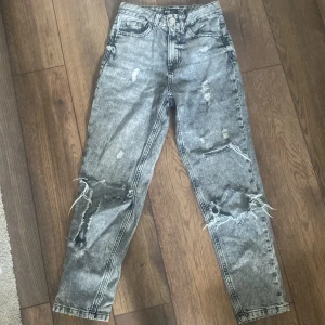 Jeans - Snygga grå mom jeans från FB Sister i storlek XXS. Jeansen har hög midja, raka ben och slitna detaljer med stora hål på knäna. Stentvättad look och klassisk femficksmodell. Perfekta för en avslappnad och trendig stil. Pris kan diskuteras💕