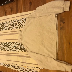 Beige offshoulder tröja Gina Tricot XS - Trendig beige tröja från Gina Tricot i offshoulder-modell med hög krage och långa ärmar. Mjuk och lite fluffig känsla i materialet, perfekt för dig som gillar en chill men snygg stil. Passar dig som vill sticka ut lite extra.