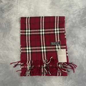 Burberry Halsduk - Skick: 7/10 (Vintage), begagnad, inga defekter. | Vad som ingår: Endast halsduken. | Ordinarie pris: +- 4000 SEK / 400 €. | ​​OBS: Halsdukarna finns i samma färgsättning men kan skilja sig något i modell eller detaljer, beroende på tillverkningsår eller kollektion