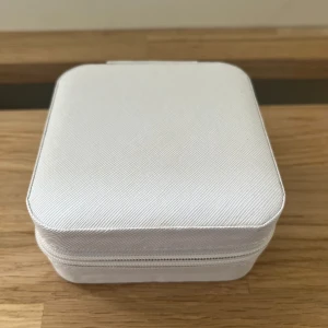 Vit smyckesask med dragkedja - Praktisk och stilren smyckesask i vit färg med dragkedja. Insidan har flera fack och rullar för ringar, samt krokar för halsband eller armband. Perfekt för att organisera dina favoritsmycken hemma eller på resan. Aldrig använd för att jag hittade mitt andra mitt andra💓💓