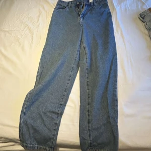 Blåa raka jeans med loose fit - Klassiska blå jeans med rak passform och loose fit. Byxorna har hög midja och är tillverkade i robust denim. Perfekta för en avslappnad och trendig look.