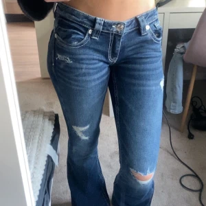 Blå bootcut jeans med slitningar - Snygga blå bootcut jeans med slitna detaljer och hål på knäna. Helt nya. Säljer dom för köpte fel storlek. Innerbenslängd 72cm
