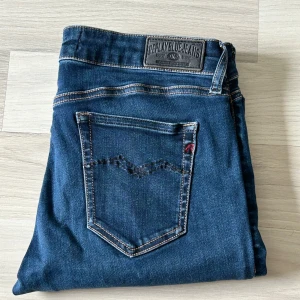 Mörkblå Replay jeans straight fit - Snygga mörkblå jeans från Replay med klassisk femficksdesign och raka ben. Jeansen har kontrastsömmar, Replay-logga på fickan och bak, samt är tillverkade i slitstarkt denim. Perfekta för dig som gillar en tidlös och clean look.