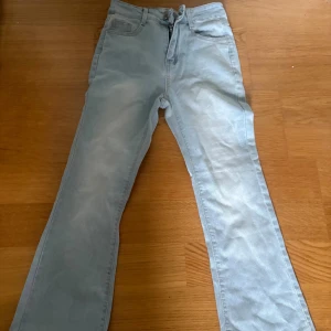 Ljusblå bootcut jeans - Snygga ljusblå jeans med klassisk femficksdesign och bootcut ben. Jeansen har normal midja och dragkedja framtill. Perfekta för en avslappnad och stilren look.