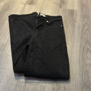 Svarta jeans - Svarta jeans från lager 157 i storlek XS med breda ben och klassisk femficksdesign. Byxorna har dragkedja och knapp framtill, samt bälteshällor. Materialet är 100% bomull för en skön och avslappnad känsla.