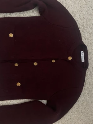 Vinröd kofta från Zara med guldknappar - Snygg vinröd kofta från Zara med rund halsringning och guldknappar framtill. 