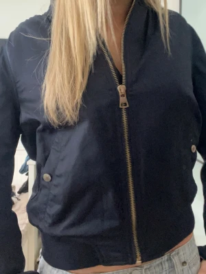 Mörkblå bomberjacka  - Mörkblå bomberjacka, ganska använd så ett fåtal defekter men inget som påverkar användningen 