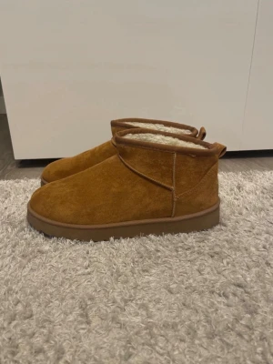 Bruna uteskor med foder. - Mysiga skor i brun mocka med mjukt, ljust foder på insidan. De har en rund tå, platt sula och klassisk design. Använda extremt få gånger, inte smutsiga eller trasiga.