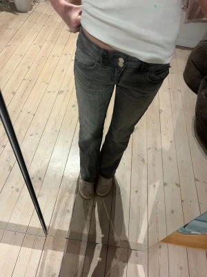 Grå lågmidjade straight jeans - Snygga grå jeans med låg midja och raka ben. Klassisk femficksmodell med knappgylf och diskreta slitningar. Perfekta till en avslappnad stil och passar till det mesta. Tillverkade i mjukt bomullsjeansmaterial. Från Gina ord pris 359 kr 