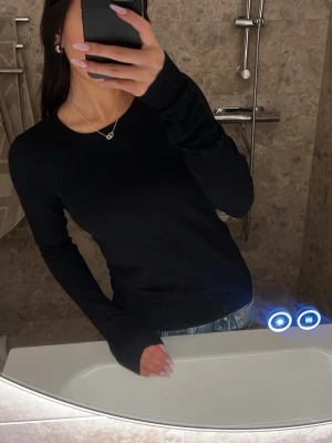 Svart basic tröja - En svart långärmad tröja med rund halsringning och ribbade muddar. Tröjan har en enkel design ich passar till allt, perfekt basplagg! Skriv ifall du vill ha fler bilder