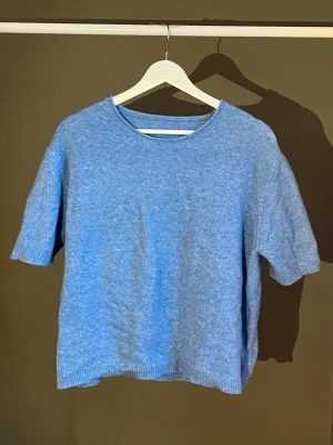 Ljusblå stickad topp med kort ärm - En enkel och stilren ljusblå stickad topp med korta ärmar och rund halsringning. Toppen har en avslappnad passform och ribbade kanter vid ärmslut och nederkant. Köpt från Sellpy, köpt i nyskick och använt ett par gånger 🩵