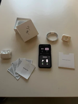 Apple AirPods Pro trådlösa hörlurar - Säljer ett par vita Apple AirPods Pro med laddningsetui, USB-C laddkabel och extra öronproppar. Hörlurarna har en stilren och kompakt design i plast och levereras med originalförpackning och manualer. Perfekta för musik, samtal och träning.