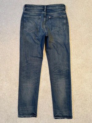 Blå H&M jeans straight fit - Säljer ett par Blå H&M jeans med straight fit och fem fickor. Jeansen har en snygg tvättad look och är tillverkade i slitstarkt bomullsjeansmaterial. I fint använt skick.