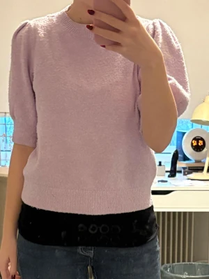Ljuslila puffärmstickad tröja - Söt ljuslila stickad tröja med puffärmar och ribbade kanter. Tröjan har rund halsringning och halvlånga ärmar som ger en trendig look. Perfekt att matcha med jeans eller kjol för en chill stil.