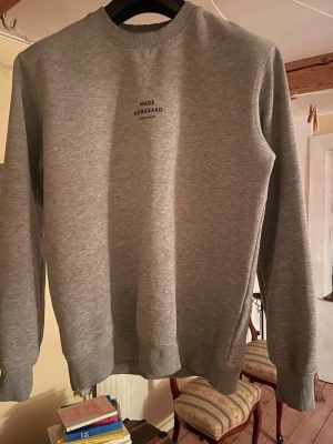 Grå sweatshirt av Mads Nørgaard - Grå sweatshirt med tryckt logotyp "MADS NØRGAARD COPENHAGEN" framtill. Ribbstickade muddar vid ärmslut och nederkant. Inga synliga tecken på användning, jag har använt den i 2 år, som i nyskick i princip. Är väldigt dryg i längden har passat mig mycket länge. Längden skulle jag säga ligger mellan M och L. Pris går att diskutera!
