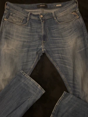 Blå Replay Rocco Jeans - Snygga blå jeans från Replay med klassisk femficksdesign och raka ben. Jeansen har ljusa slitningar framtill och bakfickor med dekorativa sömmar. Perfekta för en avslappnad och trendig look.