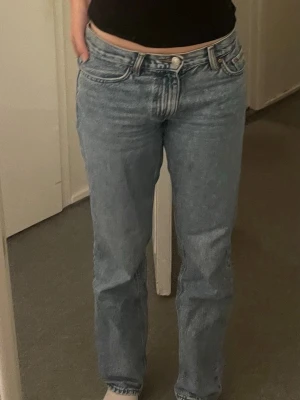 Gina Tricot blå straighta jeans - Gina Tricot jeans i ljusblå tvätt med rak passform och normal midja. Jeansen har fem fickor, knappgylf och är tillverkade i slitstarkt bomullsjeans. Perfekta för en avslappnad och tidlös look.