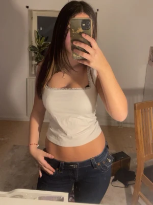 Vit linnetopp med knyt i ryggen - Säljer en vit linnetopp med smala axelband och söt spetskant upptill. Toppen har en snygg knytning i ryggen som ger en öppen rygg och croppad passform. Perfekt för dig som gillar en enkel men trendig stil.