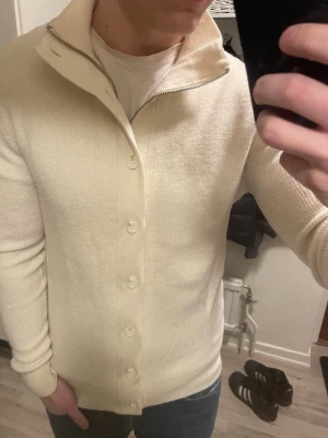 Stickad Merinoull cardigan - Otroligt fin beige/cremestickad merinoull cardigan från j.lindeberg. Passar perfekt till kallare väder. Modellen är 180cm, 75kg. Priset kan såklart diskuteras