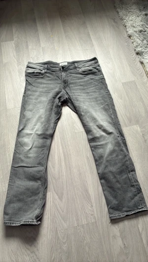  Hej! Grå raka jeans i klassisk modell - Hejj! Säljer ett par grå jeans med raka ben och fem fickor. Jeansen har en klassisk passform och subtila slitningar framtill för en avslappnad look. Perfekta till vardags och lätta att matcha med olika stilar. Den är i storlek w38 och L32 kontakta gärna vid intresse