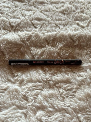 Essence Easy Brush Liner svart - Essence Easy Brush Liner är en svart eyeliner med smal spets som ger precision vid applicering. Pennan har en stilren svart design med kopparfärgad text och innehåller 0,7 ml. Perfekt för att skapa skarpa linjer och kreativa looks.
