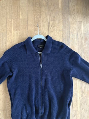 Mörkblå ziptröja från Massimo Dutti - Mörkblå stickad ziptröja från Massimo Dutti med klassisk krage och hel dragkedja framtill. Bra skick, inga defekter. 