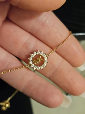 Armband från Michael Kors  - Snyggt armband i guldton från Michael Kors ett runt hänge dekorerat med gnistrande strass och bokstäverna MK i mitten. Kedjan är tunn och elegant, perfekt för att ge en lyxig touch till din outfit.