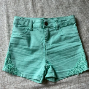 Turkos short med blommdetalj - Den är för 6-7 år gammal, men kan passa för äldre också, är 1,47 cm den passa mig jättebra. Är lite för liten. Turkos shorts med blomm detaljer vid kanten.