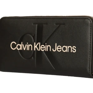 CK Calvin Klein Jeans plånbok - Begagnat skick  Plånbok sculpted zip around svart.   En längre plånbok med logo frambåde tryckt och präglat, plats för 8 kort samt sedlar och mynt.  Mått:19 x 9,5 x 2 cm