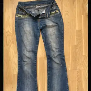 Ett par låga bootcut jeans med coola detaljer på fickorna⚡️ Storlek 176, sitter bra på mig som är 173. Knappen där fram har lossnat (se bild 3), men det går bra att sätta på en ny! Hör av dig vid frågor