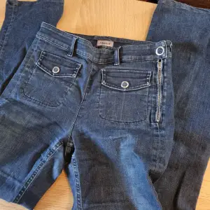 Högmidjade mörkblå jeans i lite rakare, bred modell. Ganska hög midja. Ser mindre ut på bilden men jag uppskattar att midjan passar allt från W26-W28 mkt stretch. Labeled as sz Small